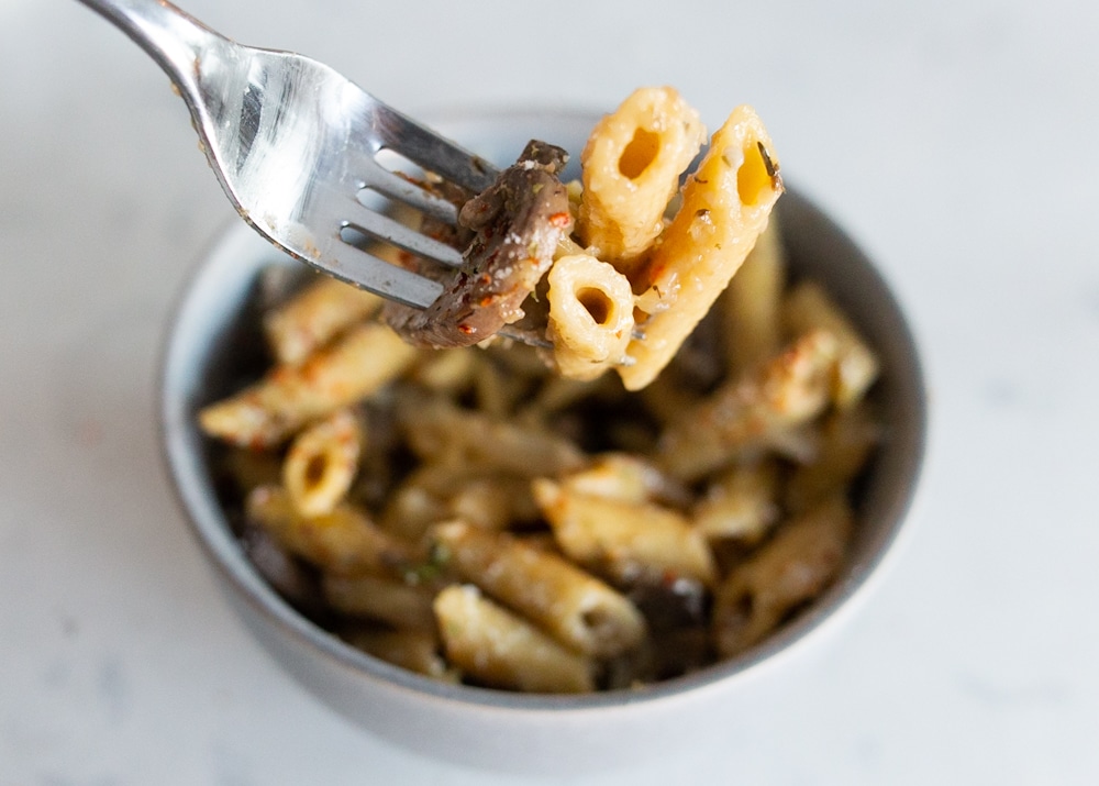 A forkfull of penne and mushroom pasta.