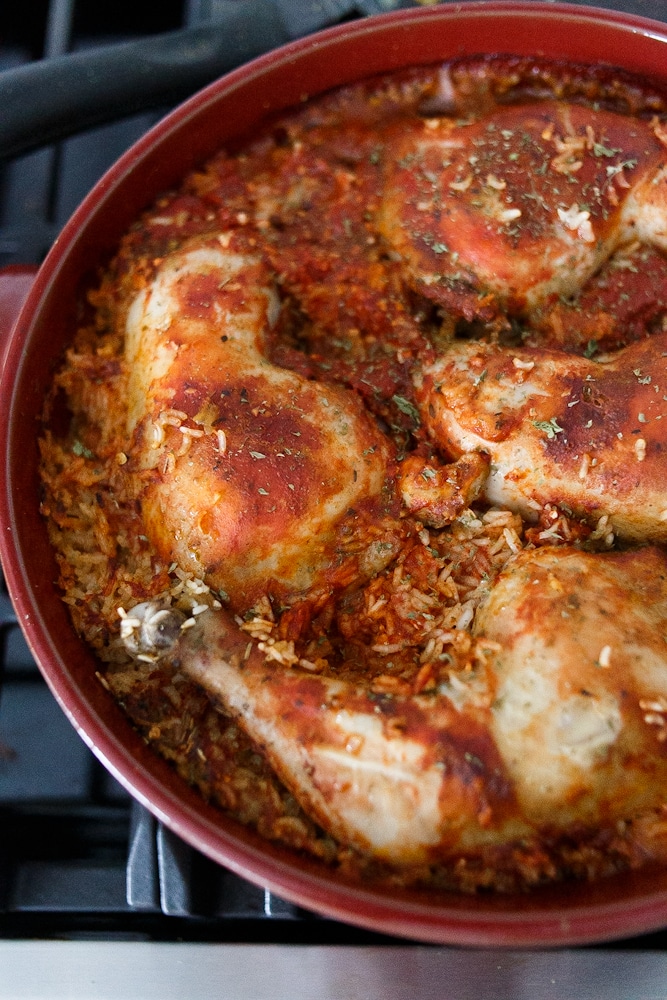 One pot chicken and rice: A red Dutch oven, with red coloured rice and chicken on top.