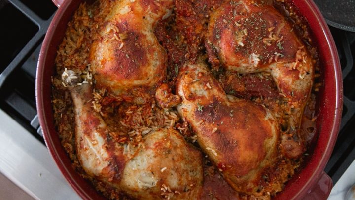 One pot chicken and rice: A red Dutch oven, with red coloured rice and chicken on top.