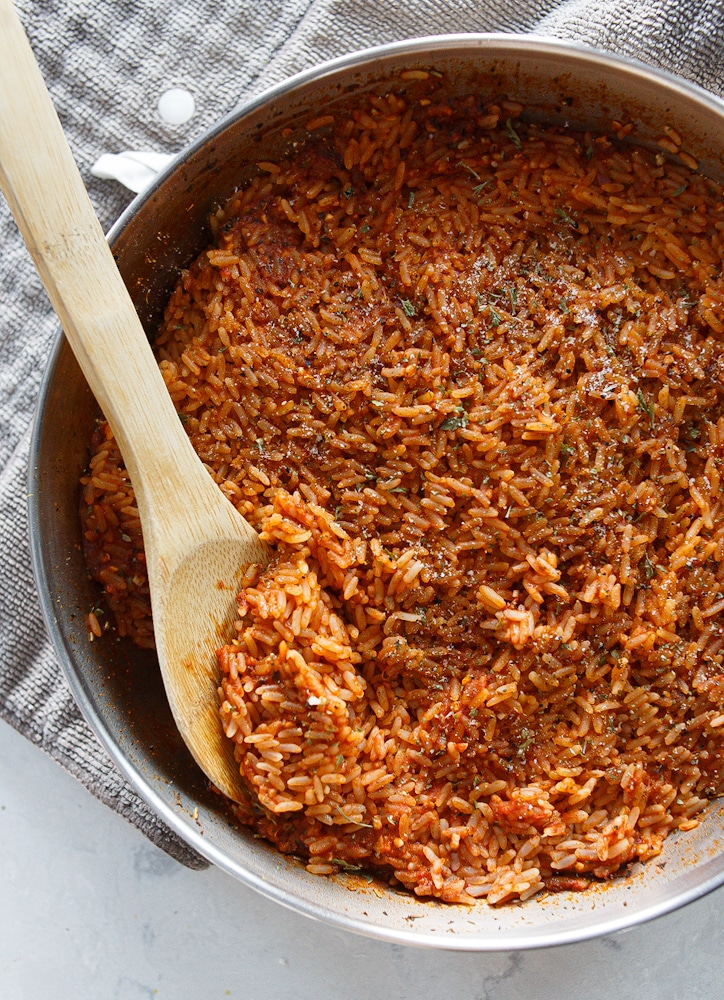 A pan filled with tomato rice. It looks like rice topped with parsley.